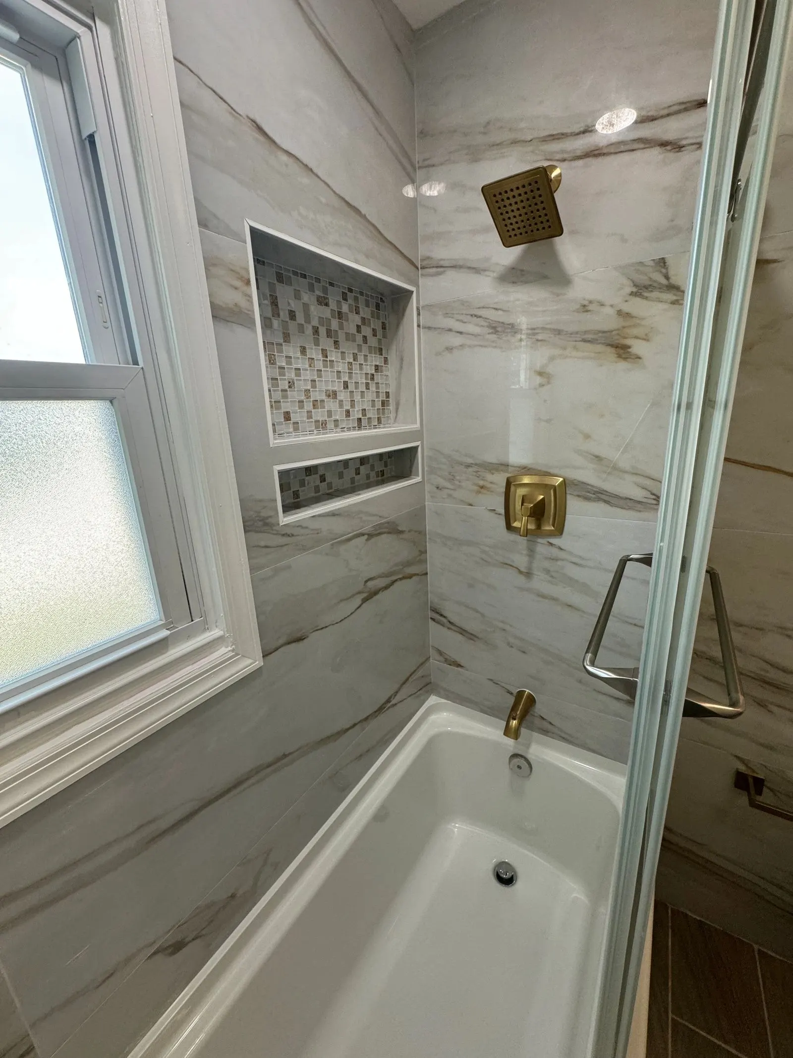 Shower and tub wall with a tiled niche and gold fixtures