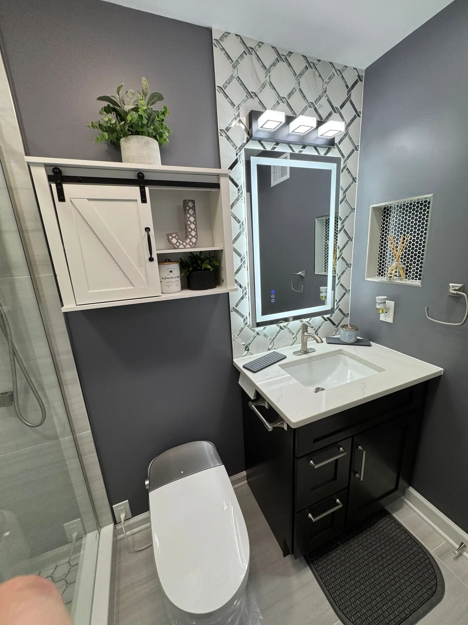 Vanity with a lighted mirror and a barn-door cabinet
